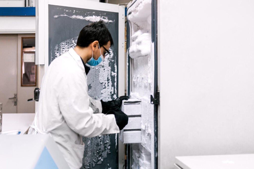 Lab technician removing sample racks from a frosted ultra-low temperature freezer in a biorepository