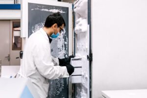 Lab technician removing sample racks from a frosted ultra-low temperature freezer in a biorepository