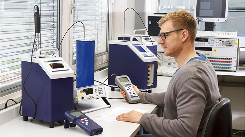 Technician calibrating temperature instruments at a laboratory bench